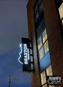 Exterior blade sign showcasing business name and logo, illuminated for enhanced visibility