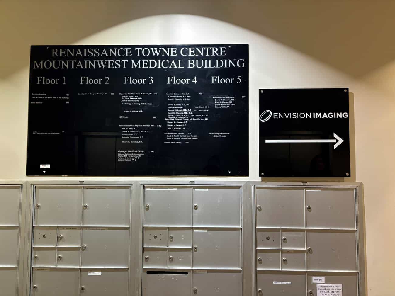 A black directory sign for Renaissance Towne Centre MountainWest Medical Building lists offices by floor above a row of gray mailboxes; a sign for Envision Imaging with a right arrow is on the wall.