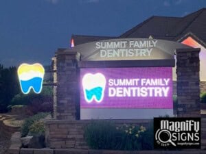 Illuminated Summit Family Dentistry sign with a tooth graphic, located outdoors on a stone base, with part of the dental office building visible in the background. Magnify Signs logo appears in the bottom right corner.