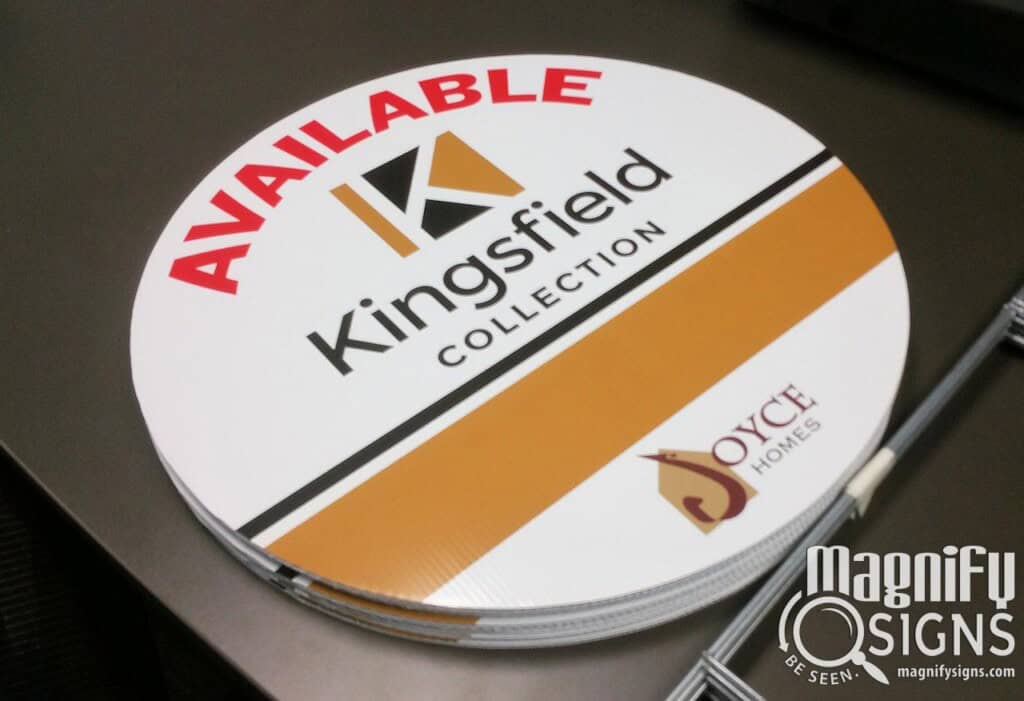 A round, white sign on a table reads AVAILABLE Kingsfield COLLECTION with gold and black accents, and logos for Joyce Homes and Magnify Signs are visible in the corners.