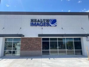 A storefront with large windows and a sign reading “HEALTH IMAGES” with a blue logo above the entrance, set against a clear, sunny sky.