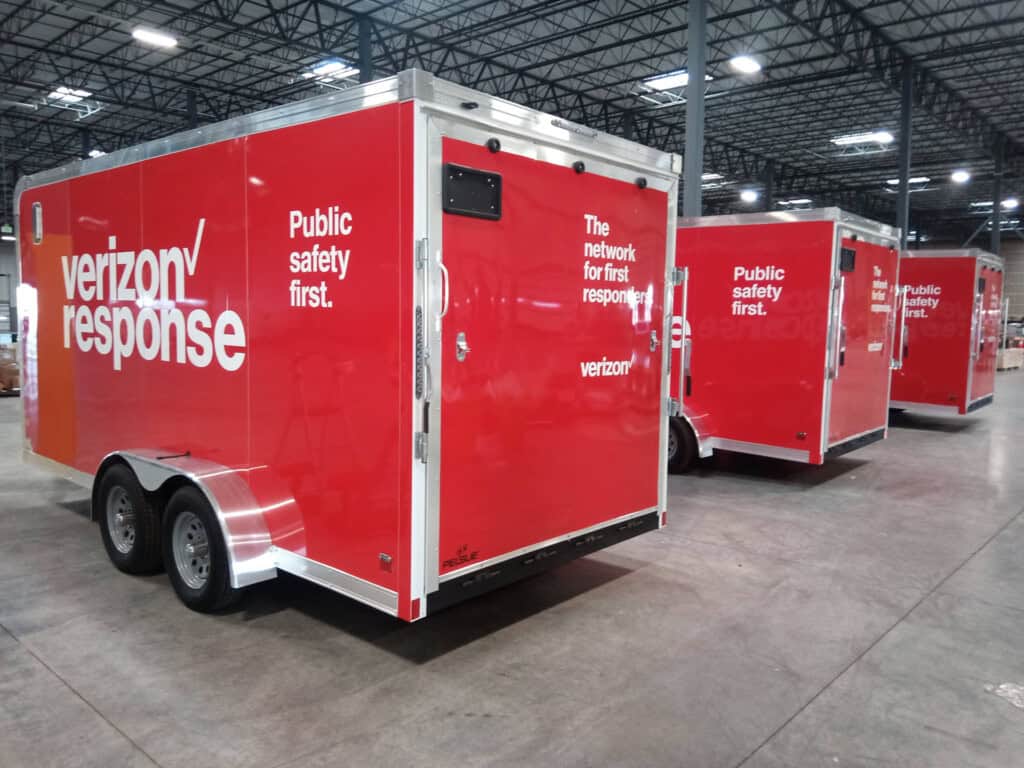 Three red Verizon Response trailers with the phrases Public safety first. and The network for first responders parked inside a large warehouse.